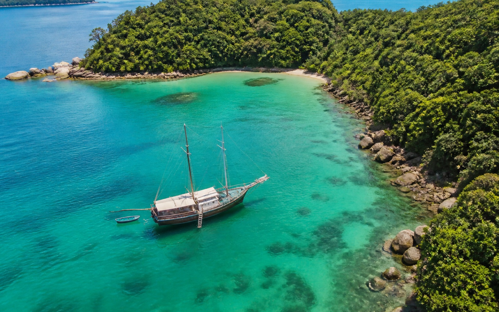 Goleta anclada en aguas turquesas entre las islas verdes de Angra dos Reis